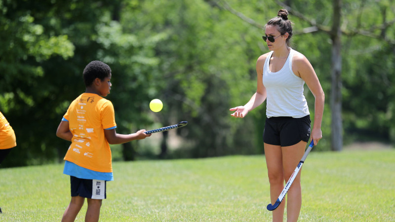 Coach helping camper with an activity outdoors