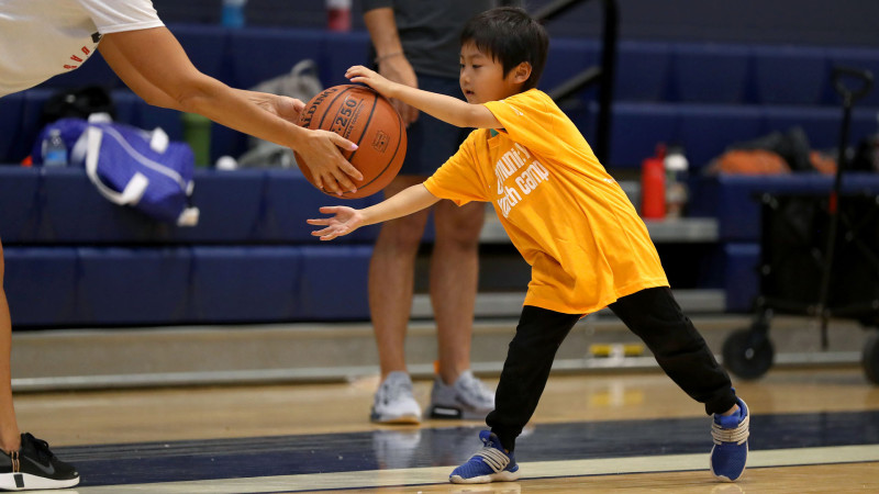 camper grabbing a basketball from coach