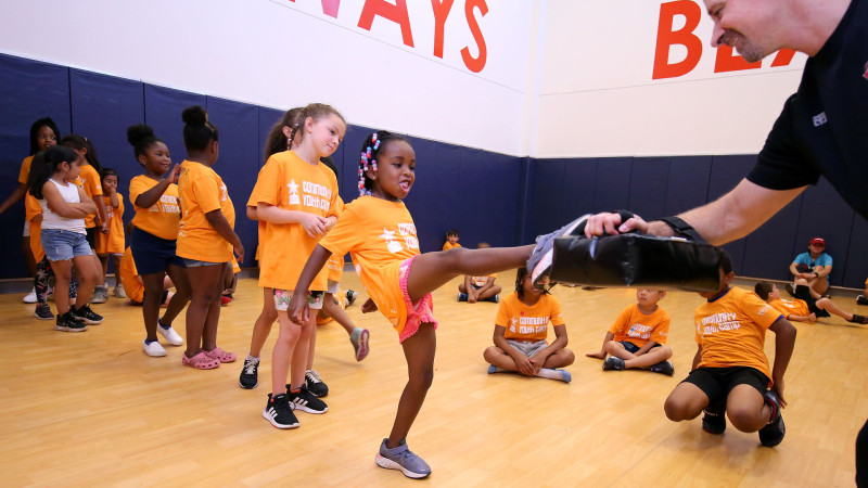 young camper kicking a karate pad