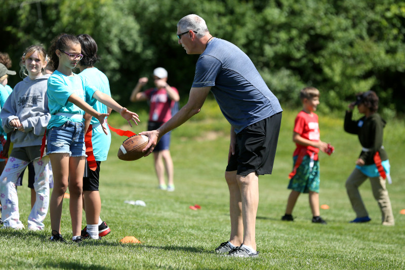 Coach helping camper with an activity outdoors