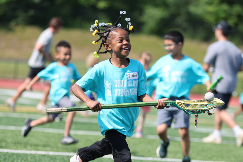 Coach holding up a bike next to a group of kids