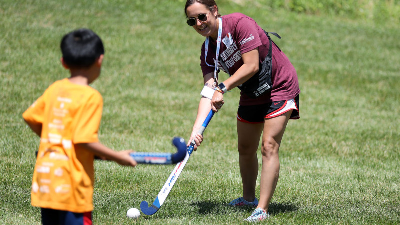 Instructor playing field hockey with young camper