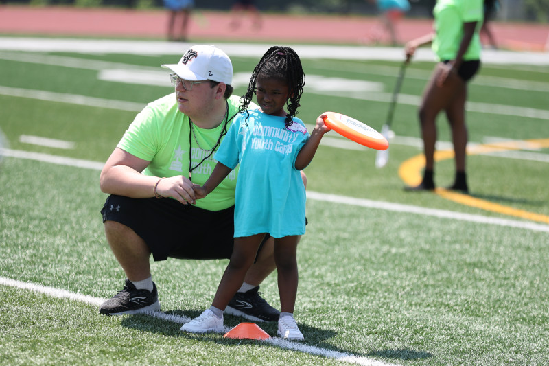 Instructor playing field hockey with young camper